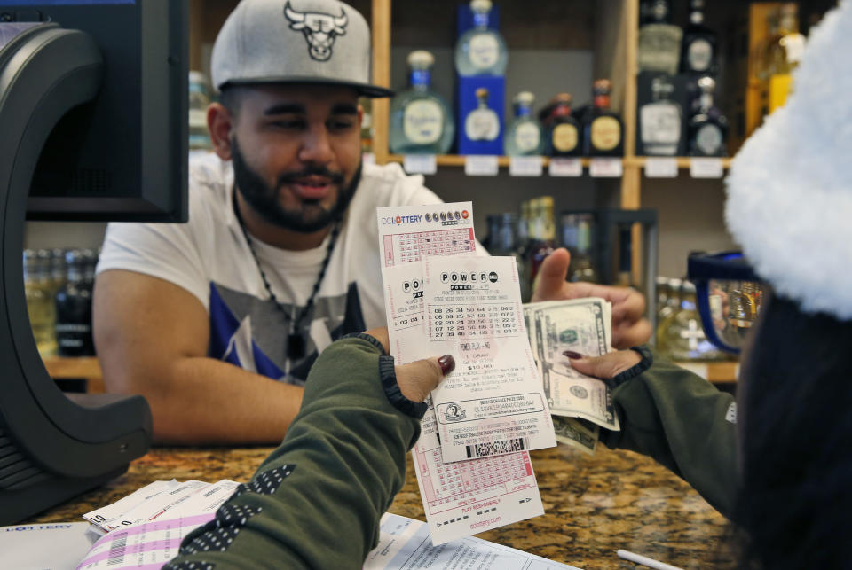 Samir Akhter, the owner of Penn Branch Liquor, exchanges money for Powerball tickets, Saturday, Jan. 9, in Washington. (Alex Brandon/AP Photo)