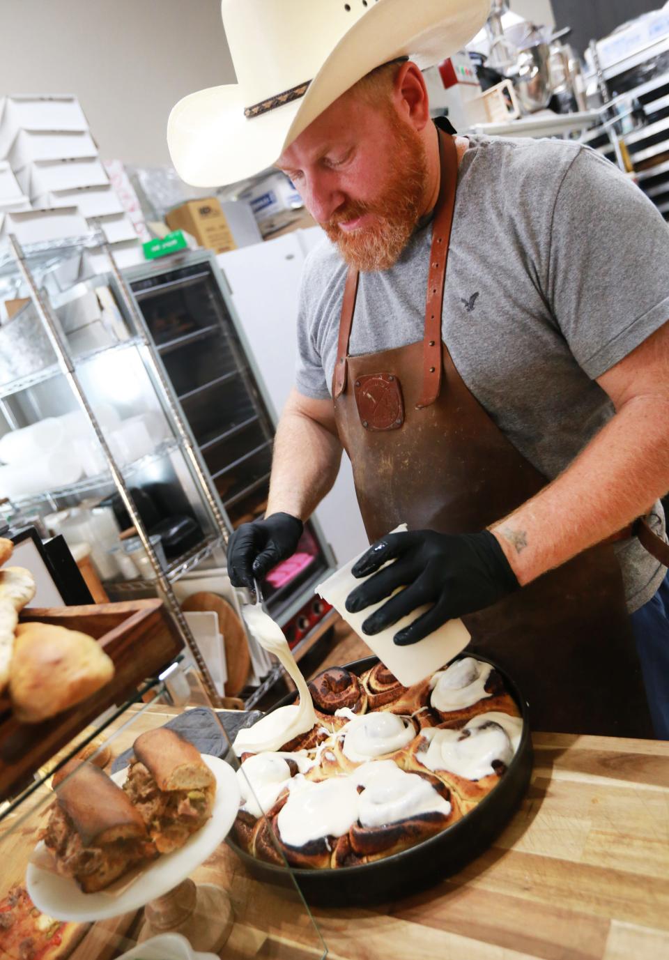 Paul Booras glazes a pan of cinnamon rolls at Rehoboth Baking Co on Sunday, Sept. 4, 2022.