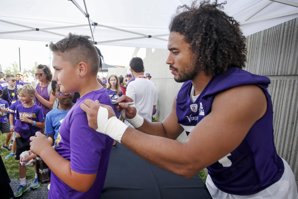 Minnesota Vikings linebacker Eric Kendricks, right, signs the shirt of a fan after drills at the NFL football team's practice facility in Eagan, Minn., Saturday, July 30, 2022. (AP Photo/Bruce Kluckhohn)