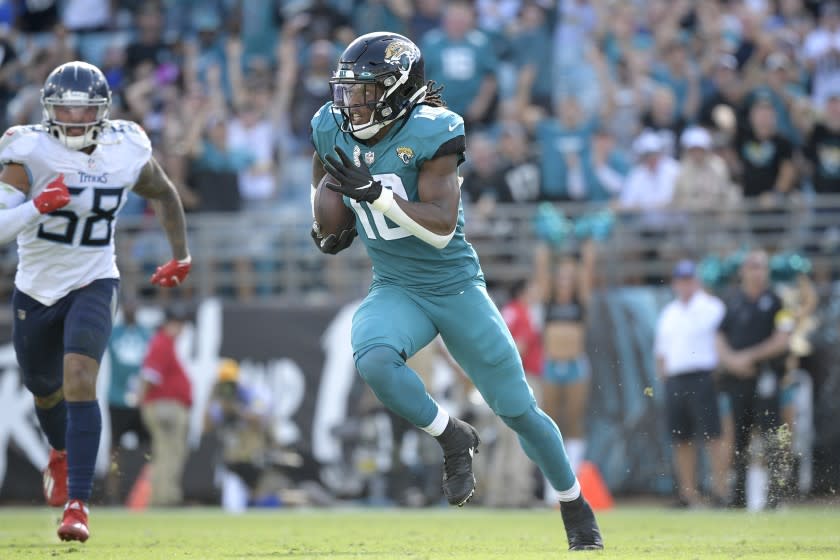 Jacksonville Jaguars wide receiver Laviska Shenault Jr. (10) runs in front of Tennessee Titans outside linebacker Harold Landry (58) after catching a pass during the second half of an NFL football game, Sunday, Oct. 10, 2021, in Jacksonville, Fla. (AP Photo/Phelan M. Ebenhack)