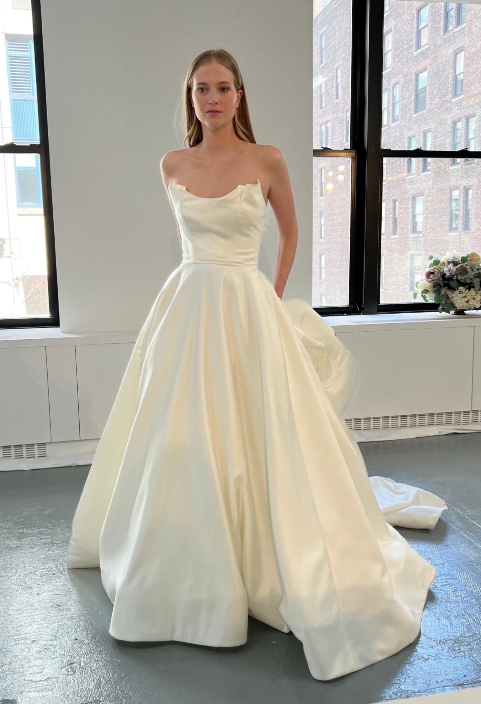 A woman poses in a strapless wedding dress with a full skirt.