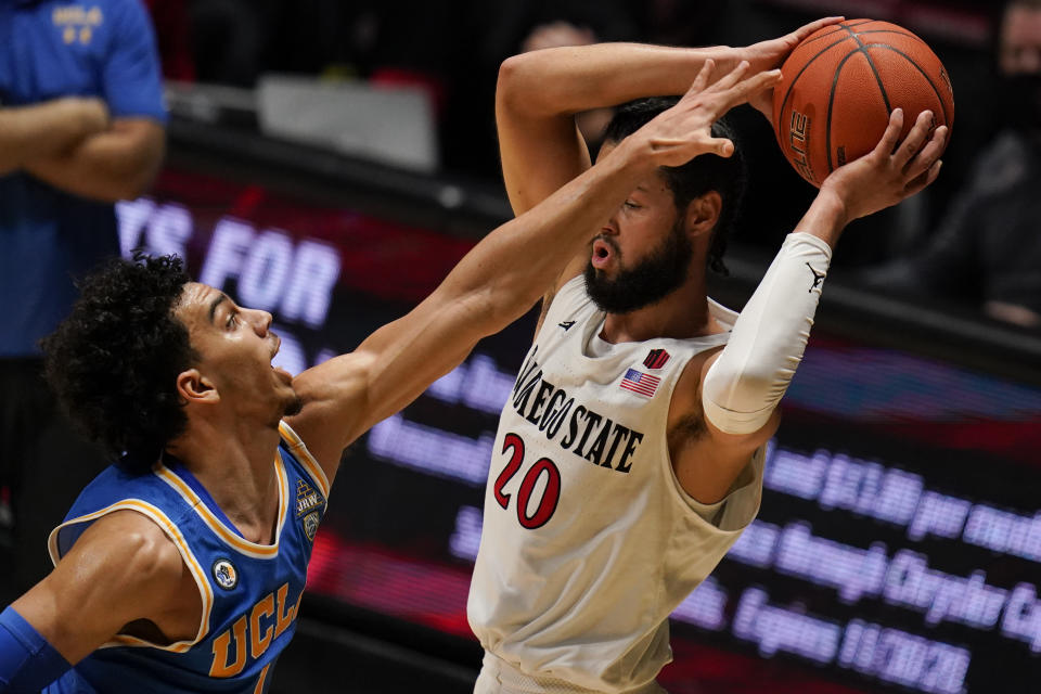 UCLA guard Jules Bernard, left, reaches for the ball as San Diego State guard Jordan Schakel (20) looks to pass it during the first half of an NCAA college basketball game Wednesday, Nov. 25, 2020, in San Diego. (AP Photo/Gregory Bull)