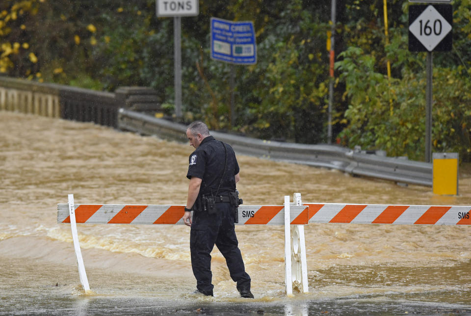 A Charlotte-Mecklenburg police officer blocks West Blvd. from local traffic as floodwater blocks the road in Charlotte, N.C., Thursday, Nov. 12, 2020. Tropical Storm Eta dumped blustery rain across north Florida after landfall Thursday morning north of the heavily populated Tampa Bay area, and then sped out into the Atlantic off of the neighboring coasts of Georgia and the Carolinas. (Jeff Siner/The Charlotte Observer via AP)