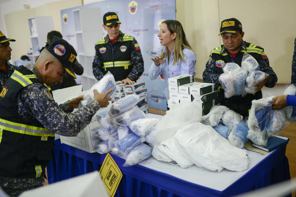 Members of Bolivarian Immigration National Police unpack biosafety supplies that include infrared thermometers, protective masks and gloves, part of preparations to help prevent the spread of the new coronavirus, at the National Experimental Security University in Caracas, Venezuela, Friday, March 13, 2020. For most people, the new coronavirus causes only mild or moderate symptoms, such as fever and cough. For some, especially older adults and people with existing health problems, it can cause more severe illness, including pneumonia. (AP Photo/Matias Delacroix)