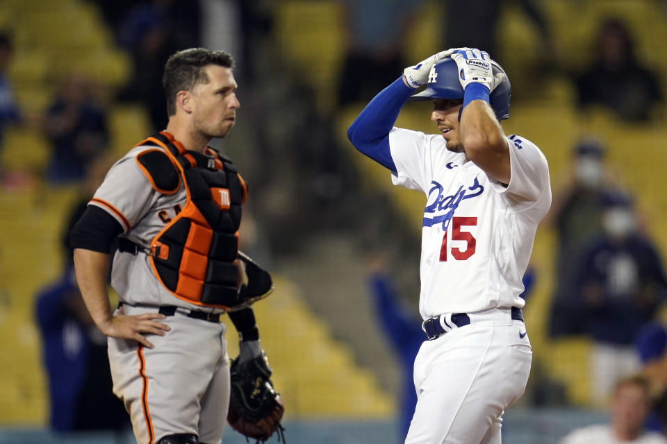 Los Angeles Dodgers' Austin Barnes grabs his helmet as he reaches home plate past San Francisco Giants catcher Buster Posey after Barnes three-run home run during the ninth inning of a baseball game Friday, May 28, 2021, in Los Angeles. (AP Photo/Marcio Jose Sanchez)