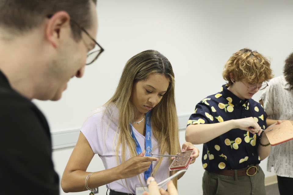 In this photo provided by the American Academy of Dermatology, AAD Pathways Career Prep students Sydney Sharpe and Dandelion Risch practice common dermatologic procedures like biopsies and sutures during a hands-on bioskills workshop offered in collaboration with Nth Dimensions at the George Washington University Student Center in Washington on July 14, 2023. (Joshua Lee Reed/AAD via AP)