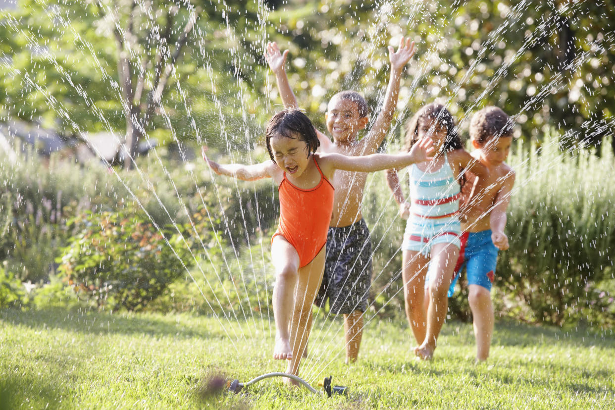 Children running through water sprinkler. (Photo: Getty)