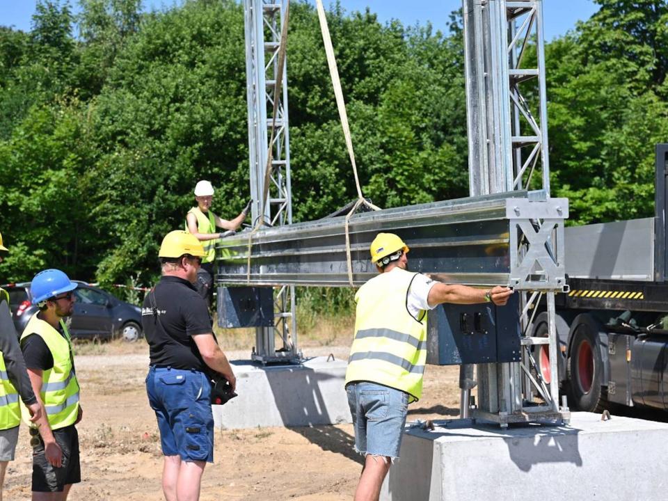 Construction workers moving a 3D printer as other stand around.