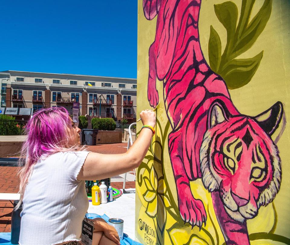 Madison Perry of Columbus paints a tiger with florals during the debut of the Open Air Arts Studio at the Creekside Blues & Jazz Festival on June 18.