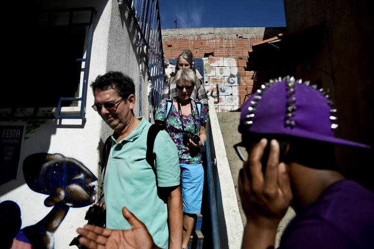 Reginaldo Spionola (R), guide and resident of the Cova da Moura neighborhood in Amadora, on the outskirts of Lisbon, walks with a group of tourists during a sightseeing tour of the area, on October 23, 2014