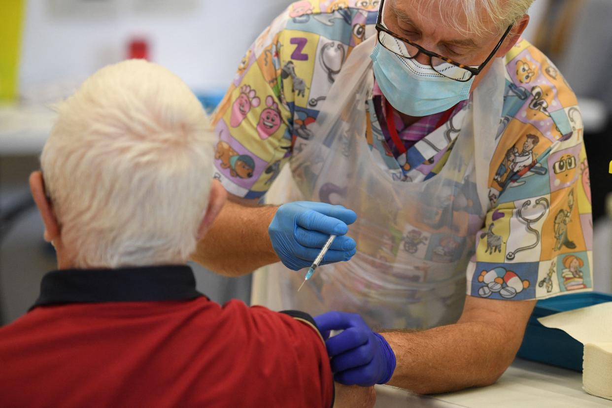 A health worker administers a dose of the BioNTech/Pfizer covid-19 vaccine at a vaccination clinic set up inside the Derby Arena at Pride Park in Derby, Derbyshire on March 31, 2021. - On March 28, 2021, Britain passed the milestone of giving the first vaccine dose to more than 30 million adults, and the government plans to allow outdoor drinking in pub gardens and non-essential retail such as hairdressers in England from April 12. (Photo by Oli SCARFF / AFP) (Photo by OLI SCARFF/AFP via Getty Images)