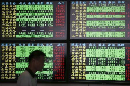 An investor walks past as information displayed on an electronic screen at a brokerage house in Shanghai, China, July 3, 2015. REUTERS/Aly Song