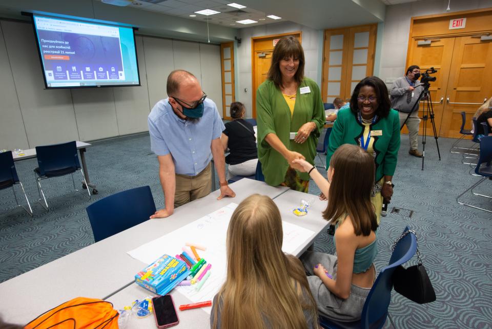 Topeka High School principal Rebecca Morrisey, middle, shakes hands with a Ukrainian student who will soon be enrolled in her school during an orientation event alongside superintendent Tiffany Anderson, right.