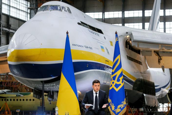 Ukrainian President Volodymyr Zelenskyy standing in front of the world&#39;s largest airplane, the Antonov An-225 Mriya.