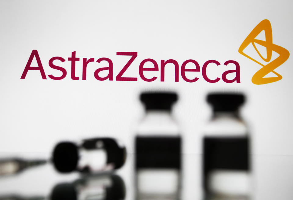 A medical syringe and vials are seen in front of AstraZeneca logo in this creative photo illustration. (Photo by STR/NurPhoto via Getty Images)