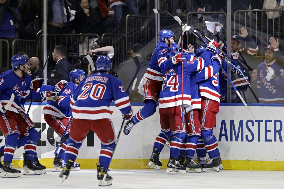 New York Rangers left wing Artemi Panarin is mobbed by teammates after scoring the game winning goal against the Pittsburgh Penguins during overtime in Game 7 of an NHL hockey Stanley Cup first-round playoff series, Sunday, May 15, 2022, in New York. The Rangers won 4-3 in overtime. (AP Photo/Adam Hunger)