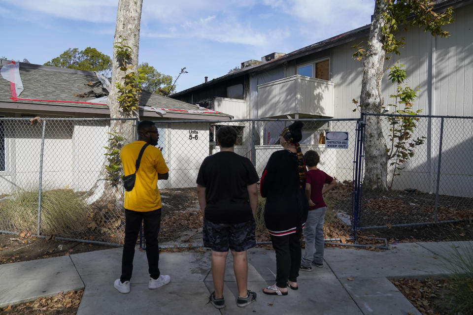 Alliance of Californians for Community Empowerment (ACCE) community organizer Devin Williams, left, talks with Kim Carlson and her two grandsons while looking at the two buildings which were destroyed by a fire in March at the Delta Pines apartment complex, Friday, Nov. 4, 2022, in Antioch, Calif. Despite a landmark renter protection law approved by California legislators in 2019, tenants across the country’s most populous state are taking to ballot boxes and city councils to demand even more safeguards. They want to crack down on tenant harassment, shoddy living conditions and unresponsive landlords that are usually faceless corporations. (AP Photo/Godofredo A. Vásquez)