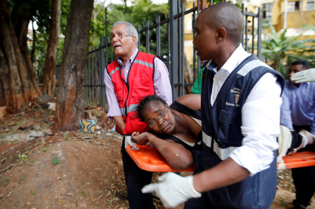 Woman is evacuated at the scene where explosions and gunshots were heard at the Dusit hotel compound, in Nairobi