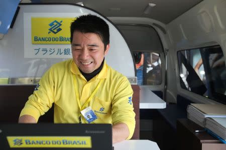 A Banco do Brasil staff member works in the bank's mobile service van at the parking lot of a Brazilian supermarket in Oizumi, Gunma prefecture, Japan April 2, 2017. Picture taken April 2, 2017. REUTERS/Lisa Twaronite