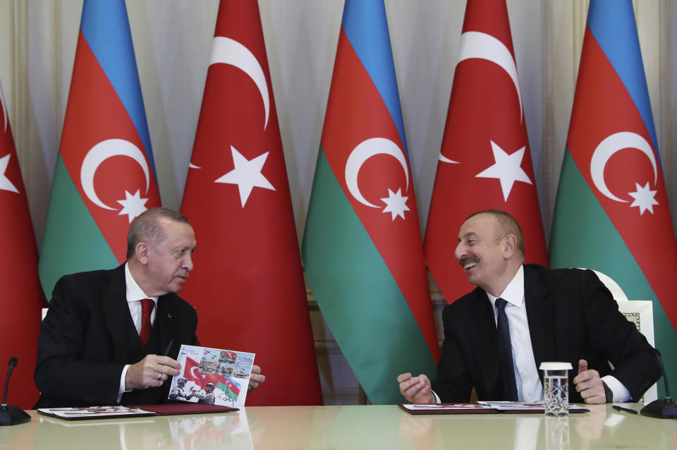 Turkey's President Recep Tayyip Erdogan, left and Azerbaijan's President Ilham Aliyev, right, talk during a joint news conference following their meeting in Baku, Azerbaijan, Thursday, Dec. 10, 2020. A massive military parade was held in celebration of the peace deal with Armenia over Nagorno-Karabakh. Erdogan attended as Turkey strongly backed Azerbaijan during the conflict, which it used to expand its clout in the region. (Turkish Presidency via AP, Pool)
