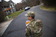 Rhode Island Air National Guard Tsgt. William Randall walks through the Watch Hill neighborhood looking for New York residents to inform them of self quarantine orders, Saturday, March 28, 2020, in Westerly, R.I. States are pulling back the welcome mat for travelers from the New York area, which is the epicenter of the country's coronavirus outbreak, and some say at least one state's measures are unconstitutional. Gov. Gina Raimondo ratcheted up the measures announcing she ordered the state National Guard to go door-to-door in coastal communities starting this weekend to find out whether any of the home's residents have recently arrived from New York and inform them of the quarantine order. (AP Photo/David Goldman)