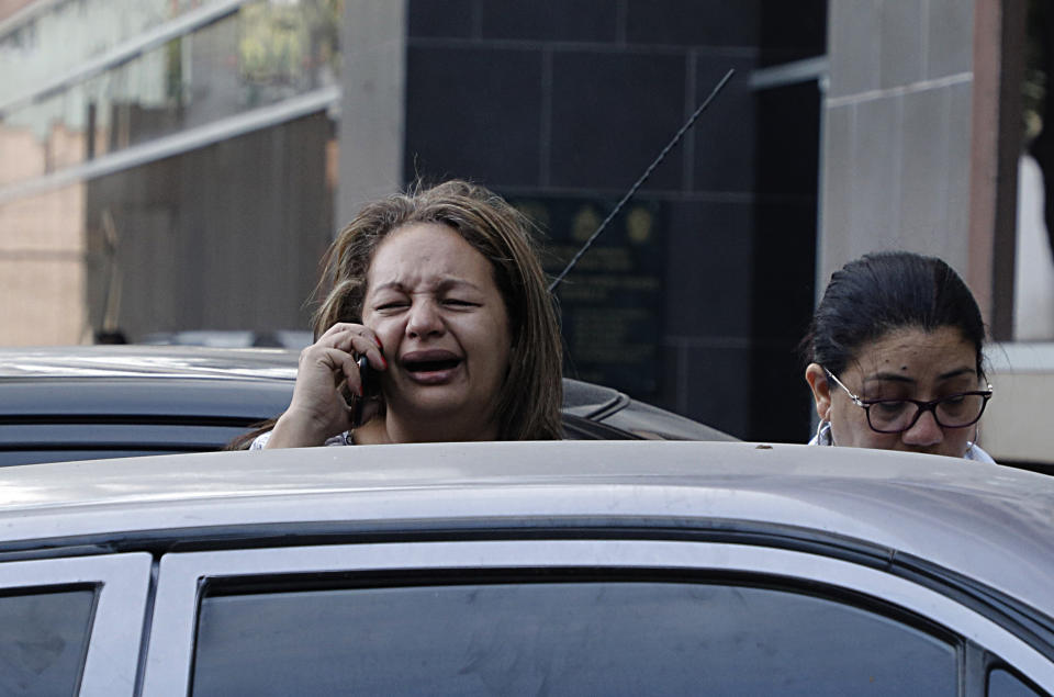 A woman who just learned that her brother Edin Alexis Hernandez is one of the prisoners who died the previous day in a riot inside El Porvenir prison, speaks on the phone outside the morgue in Tegucigalpa, Honduras, Monday, Dec. 23, 2019. At least 16 prisoners died during fighting inside a detention center in Honduras on Sunday, two days after rioting at another prison killed 18 inmates, authorities said. (AP Photo/Elmer Martinez)