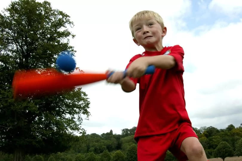 young boy hitting ball with bat