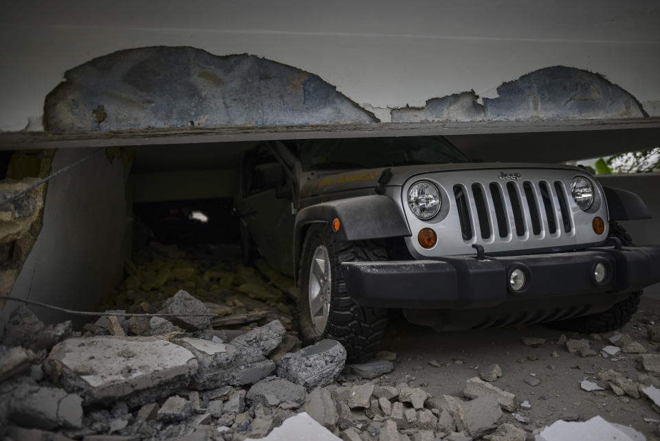 A car is crushed under a home that collapsed after the previous day's magnitude 6.4 earthquake in Yauco, Puerto Rico, Wednesday, Jan. 8, 2020. More than 250,000 Puerto Ricans remained without water on Wednesday and another half a million without power, which also affected telecommunications. (AP Photo/Carlos Giusti)