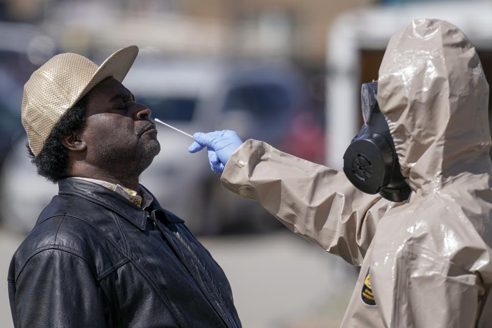 FILE - In this May 11, 2020, file photo, Wisconsin National Guard members administer COVID-19 tests in a parking lot in Milwaukee. The coronavirus tightened its grip on the American heartland, with hospitals in Wisconsin and North Dakota running low on space, and the NFL postponing a game over an outbreak that's hit the Tennessee Titans football team. (AP Photo/Morry Gash, File)