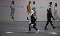 FILE - In this Monday, May 11, 2020 file photo, a woman and man walk past each other on a main shopping street in Antwerp, Belgium. The European Union executive announced Thursday, March 4, 2021 that it wants to force employers to be much more open about how much money staff makes to make it easier for women to challenge wage imbalances and further closer the gender pay gap. The EU made it clear that women workers had been disproportionally affected by the pandemic, many having to add more home tasks to their work schedule because of closure of schools and day care centers. (AP Photo/Virginia Mayo, File)