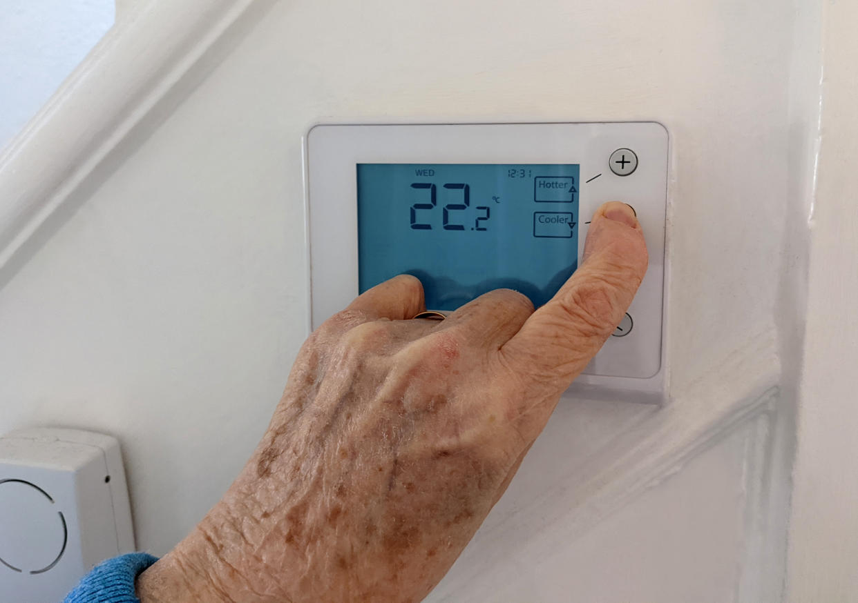 Cost of living: Elderly person turning down the central heating with a wireless thermostat