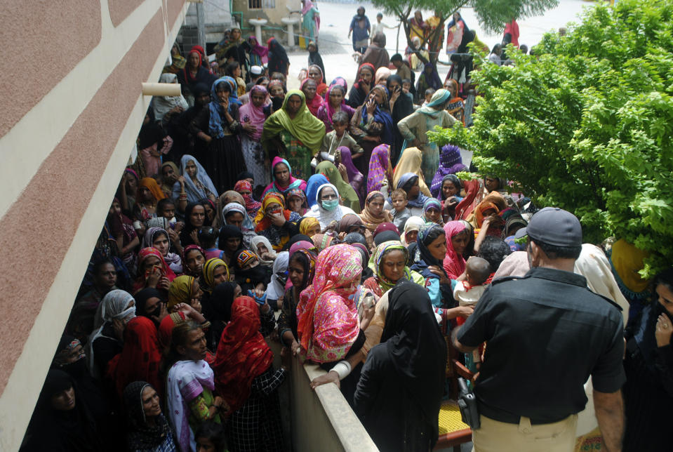 Flood affected people wait to receive for relief aid in Dadu district of Sindh Province in southern Pakistan, Saturday, Aug. 27, 2022. Officials say flash floods triggered by heavy monsoon rains across much of Pakistan have killed nearly 1,000 people and displaced thousands more since mid-June. (AP Photo/Pervez Masih)