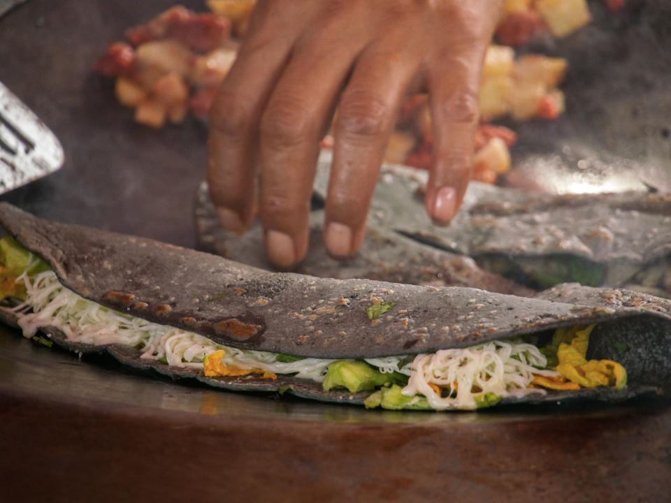 A person making blue corn tortilla quesadillas.