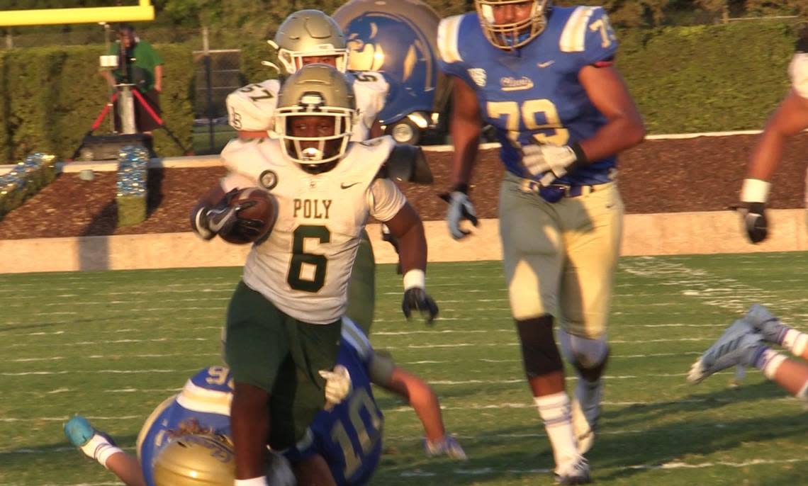 Clovis’ John Villanueva, 10, and Noah Luginbill, 16, tackles Devin Samples, 6, of Long Beach Poly at Lamonica Stadium on Thursday, Aug. 18, 2022.