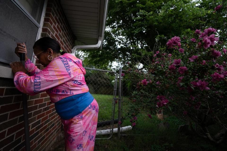 Cahokia Heights resident Yvette Lyles rests on a shovel’s handle in her yard. Her property has flooded with sewage-contaminated water for decades. Each time, she rinses her home’s exterior and driveway with a garden hose. She shovels debris near her yard to the street drain so passing cars can’t splash it onto the house. Inside, she pumps water out of her crawl space, vacuums debris and bleaches walls and floors.