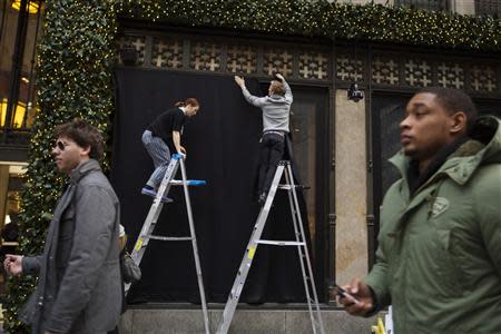 Workers hang black curtains over holiday windows before their unveiling at Saks Fifth Avenue in New York, November 22, 2013. REUTERS/Lucas Jackson