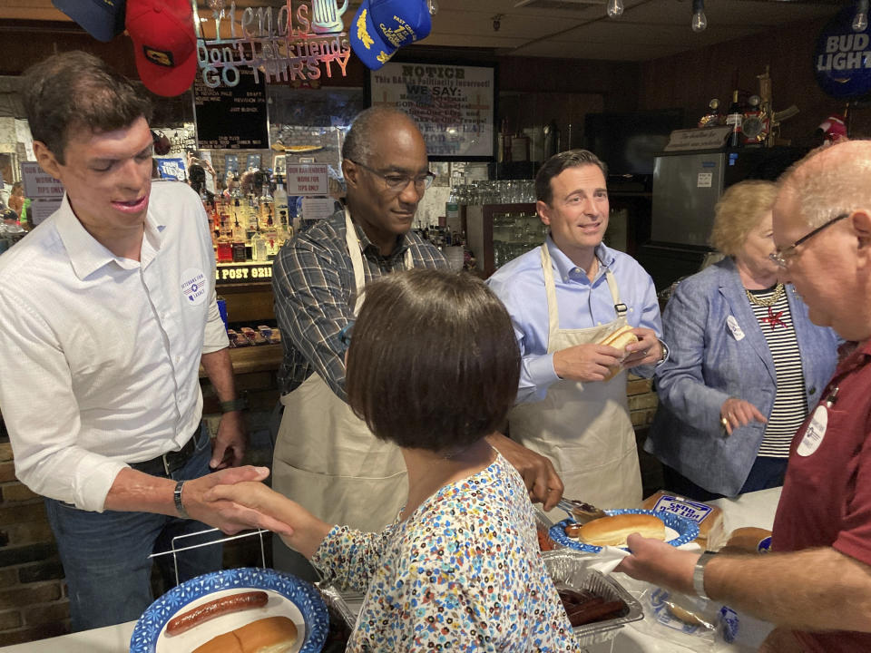 Retired Army Capt. Sam Brown, left, Air Force Col. Tony Grady, center, and Nevada Republican Senate candidate Adam Laxalt, right, greet veterans and their guests while serving up free hotdogs at the VFW post in Reno, Nev., on Sept. 1, 2022. Brown, who was nearly killed during combat in Afghanistan and lost the GOP Senate primary to Laxalt, is now rallying behind the campaign of Laxalt, who served as a Navy Judge Advocate General in Iraq and is trying to unseat Sen. Catherine Cortez Masto, D-Nev. (AP Photo/Scott Sonner)