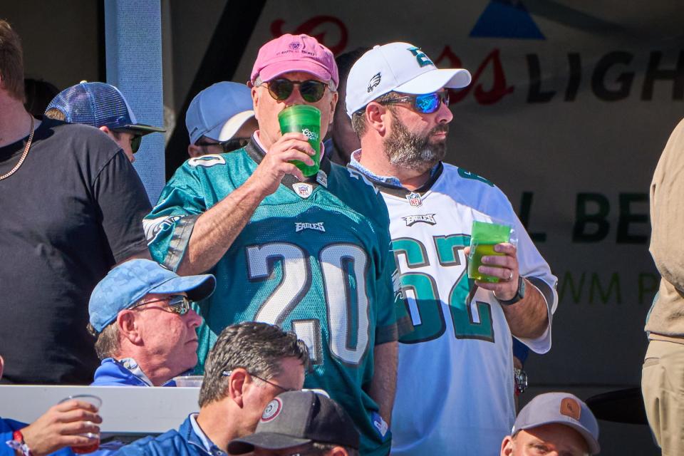 Two Philadelphia Eagles fans enjoy some drinks while standing in the grandstands behind the tee box on the 16th hole during round one of the WM Phoenix Open at TPC Scottsdale on Feb. 9, 2023.