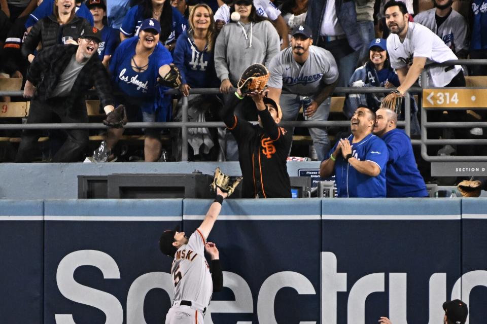 A Giants player reaches in vain for the ball after a home run.