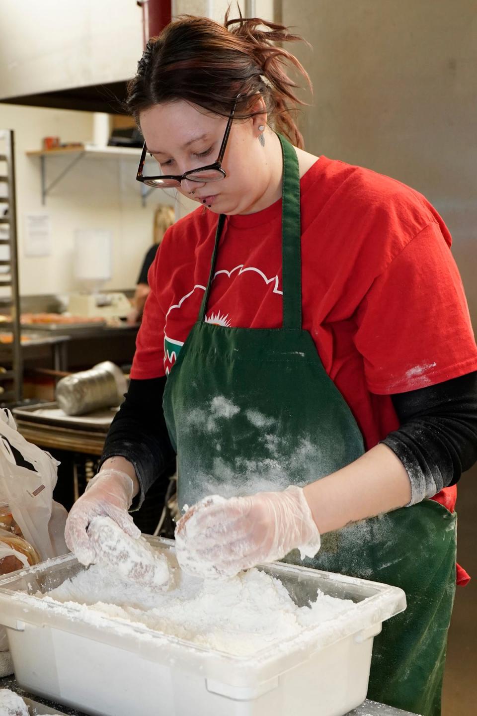 Morning Fresh Bakeries employee Hannah Kopke of Adrian adds a good amount of powdered sugar to paczki Monday afternoon in preparation for Fat Tuesday, also known as Paczki Day, which is today.