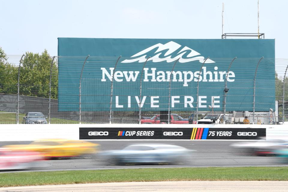 Drivers speed by a New Hampshire billboard during the 2023 NASCAR Cup Series race at New Hampshire Motor Speedway.