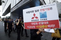 FILE - In this July 11, 2019, file photo, a protester with a banner walks to attend a rally denouncing the Japanese government's decision on their exports to South Korea in front of the Japanese Embassy in Seoul, South Korea. The modern legacy of a dark chapter in Japan’s history, when hundreds of thousands of people were brought from the Korean Peninsula and other Asian nations to work in logging, in mines, on farms and in factories as forced labor, lives on in the companies that came to dominate the Japanese economy after World War II. Many of those companies are still facing demands for compensation that they say were settled by treaty decades ago. The sign reads "The shameless Japanese company should immediately compensate for its war crimes in accordance with the Supreme Court ruling." (AP Photo/Ahn Young-joon, File)