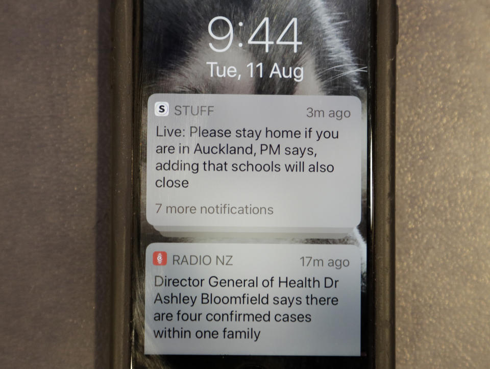 A news alert is displayed on a mobile phone in Christchurch, New Zealand, Tuesday, Aug. 11, 2020. New Zealand Prime Minister Jacinda Ardern said Tuesday that authorities have found four cases of the coronavirus in one Auckland household from an unknown source, the first cases of local transmission in the country in 102 days. (AP Photo/Mark Baker)