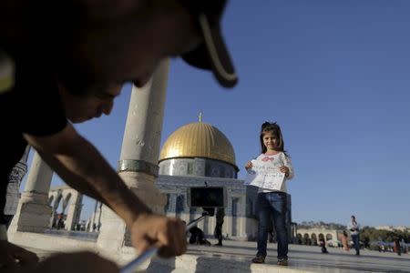 Palestinian Shadi Etmezeh (L), 25, from the West Bank village of Idna, near Hebron, takes a photo of a relative holding a note reading: "Muatasem Etmezeh the mosque misses you" in front of the Dome of the Rock on the compound known to Muslims as Noble Sanctuary and to Jews as Temple Mount, in Jerusalem's Old City, during the holy month of Ramadan, July 4, 2015. REUTERS/Ammar Awad