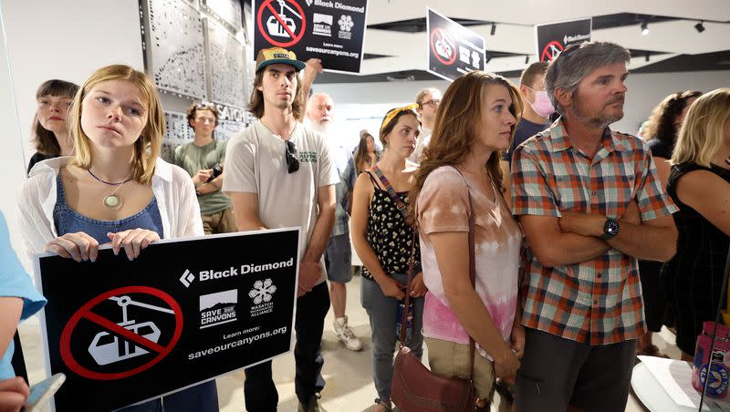 Emily Warner, left, holds a sign protesting a Little Cottonwood Canyon gondola as people make public comments on the Regional Transit Plan (RTP), and whether or not to remove the gondola from the plan, during a Wasatch Front Regional Council meeting at the WFRC in Salt Lake City on Thursday, May 25, 2023. Despite the majority of public commenters who showed up to oppose the gondola at the meeting, the WFRC voted against removing the gondola from the Regional Transit Plan (RTP.)