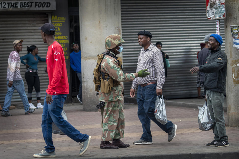 A South African National Defense Forces soldier makes sure the safe distance between people is respected in the commercial area of the Alexandra township of Johannesburg, South Africa, Friday April 3, 2020. South Africa went into a nationwide lockdown for 21 days in an effort to control the spread of the coronavirus. The new coronavirus causes mild or moderate symptoms for most people, but for some, especially older adults and people with existing health problems, it can cause more severe illness or death.(AP Photo/Jerome Delay)