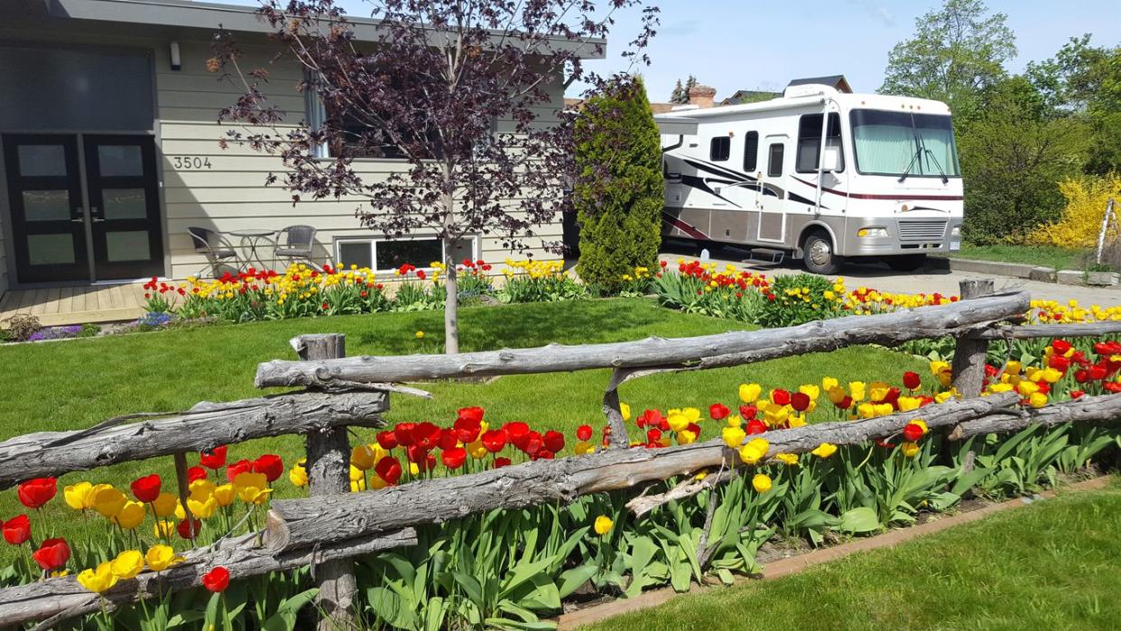 RV Parked by House and Field of Flowers