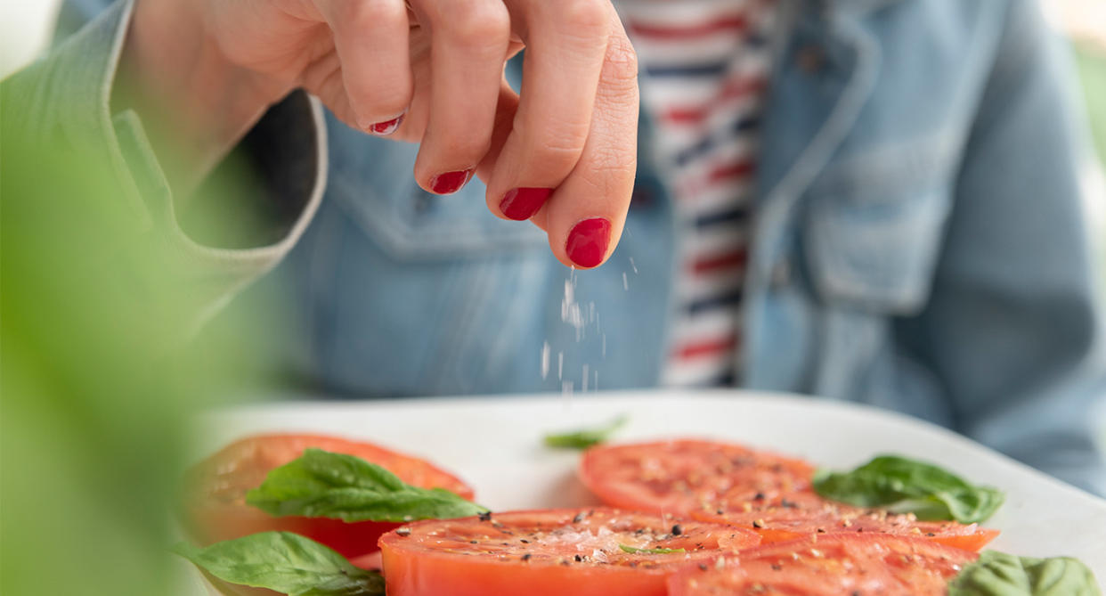 Woman putting salt on food in the heat. (Getty Images)