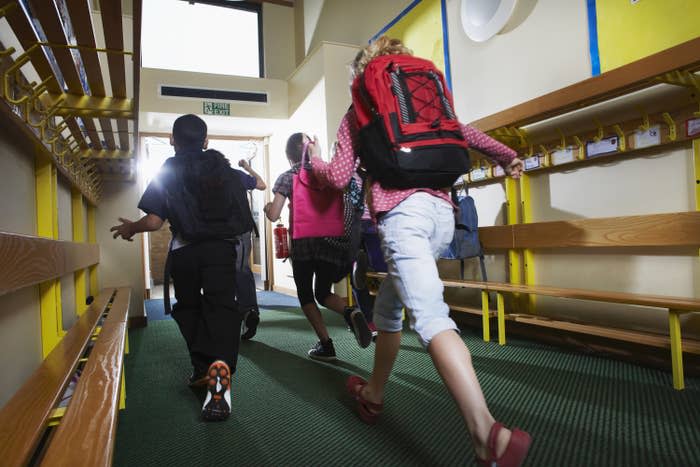 children running out of school with backpacks