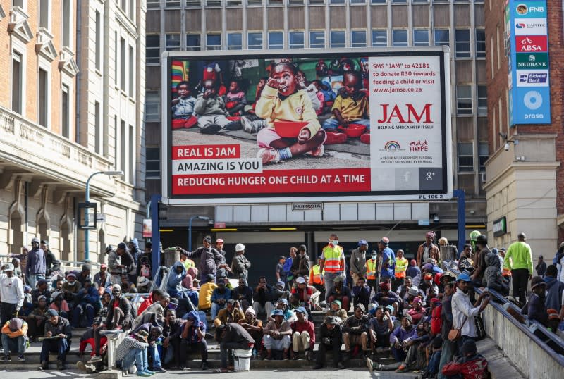 Homeless people sit while waiting to be transported to a homeless shelter in Johannesburg